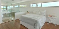 a bedroom with white walls and wood flooring has a large bed in the corner