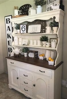 a white hutch filled with dishes and cups on top of a wooden countertop