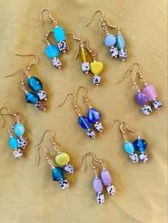 a collection of earrings with different designs and colors on them sitting on a cloth covered surface