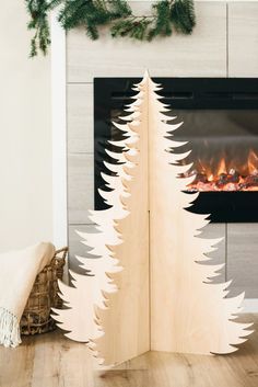 a wooden christmas tree sitting in front of a fireplace