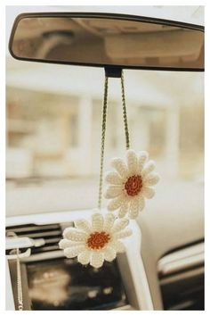 two crocheted flowers hanging from the dashboard of a car