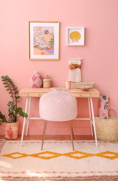 a pink room with two pictures on the wall and a desk in front of it