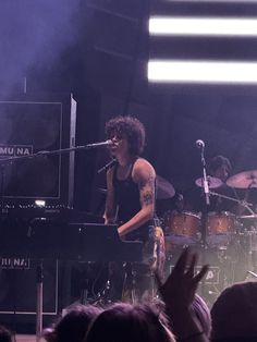 a man standing on top of a stage next to a piano and microphone in front of a crowd