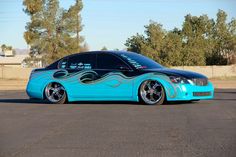 a blue car with flames painted on it's side parked in a parking lot