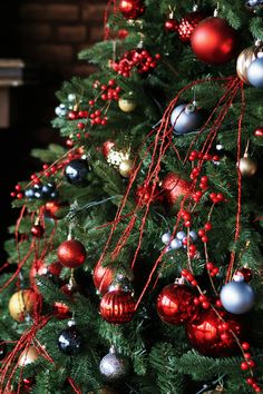 a christmas tree with red, silver and gold ornaments hanging from it's branches