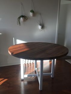 a wooden table sitting in the middle of a room with potted plants hanging on the wall