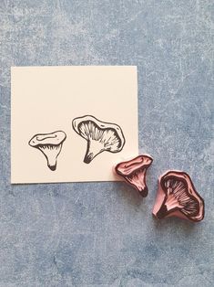 two mushrooms are sitting on top of a piece of paper next to some pink foil