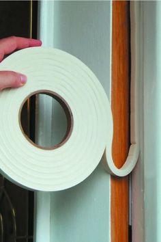 a hand holding a roll of tape near a door with the handle on it's side