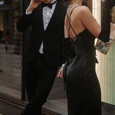 a man in a tuxedo standing next to a woman wearing a black dress