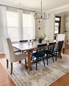 a dining room table with chairs and a rug in front of the table is surrounded by windows