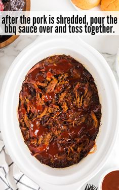 a white bowl filled with bbq sauce on top of a table next to buns