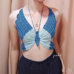 a woman wearing a blue and white crochet top with a necklace on her neck