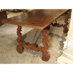 an old wooden table sitting in a room next to a white pillar and other antique furniture