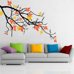 a living room filled with furniture and a tree branch wall decal on the wall