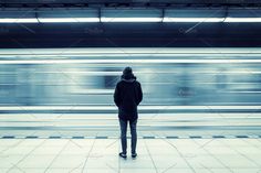 a person standing in front of a train at a station with motion blurs behind them