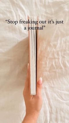 a person holding an open book in their hand with the text stop freaking out it's just a journal