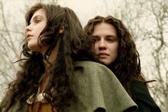 two women standing next to each other with long hair on their shoulders and one wearing a green shawl