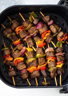 the skewers are being cooked on the grill with peppers, onions and meat