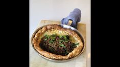 a pie with meat and vegetables in it on a table next to a blue glove