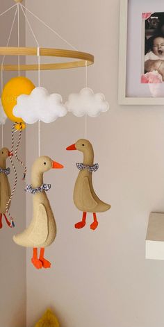 two ducks are hanging from a mobile in the shape of a sun and clouds, with a baby's crib next to them