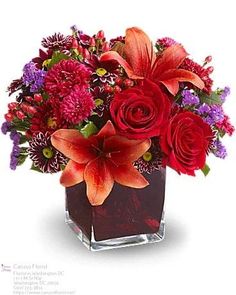 a square vase filled with red and orange flowers