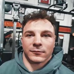 a man standing in front of a gym equipment rack with his head tilted to the side