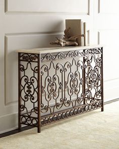 an ornate iron console table in a living room with white walls and beige carpeting