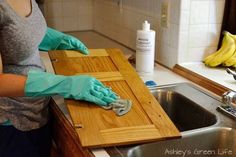 a woman in blue gloves is cleaning a wooden counter top with a sponge and rag