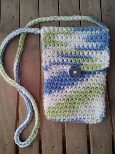 a crocheted bag sitting on top of a wooden table next to a button