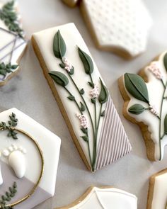 some cookies decorated with flowers and leaves on top of a white table next to each other