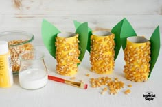 corn on the cob in vases made out of paper and construction supplies next to it