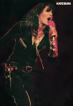 a man with long hair holding a microphone in his right hand and wearing leather pants