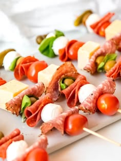 several skewers of meat and vegetables on a white plate