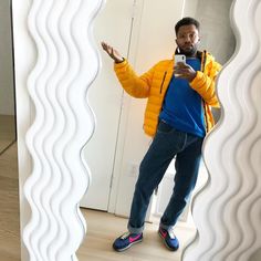 a man standing in front of a mirror taking a selfie with his cell phone