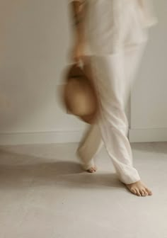 a blurry photo of a person in white pants and shirt with one foot on the ground