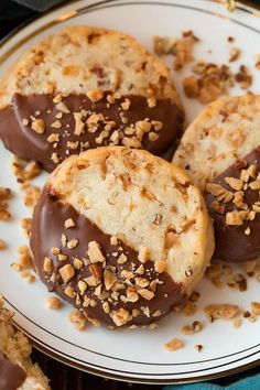 three chocolate covered cookies sitting on top of a white and gold plate with pecans