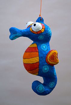 a blue and orange seahorse ornament hanging from a string on the water