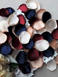 a bunch of different colored flowers on a white tablecloth with one flower in the middle