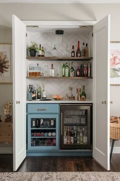 an open cabinet with liquor bottles and glasses on the shelves in a home bar area