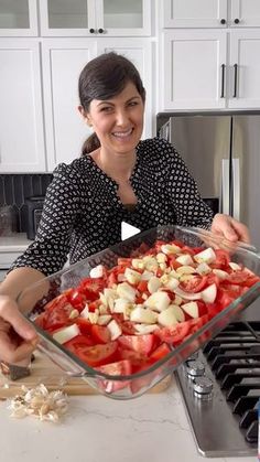 a woman holding a pan full of chopped vegetables