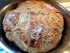 a loaf of bread with sesame seeds in a metal bowl on a stovetop top