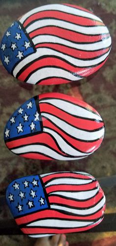 two red, white and blue painted rocks with american flags on them are sitting next to each other