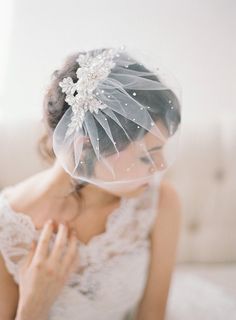 a woman in a wedding dress is wearing a veil and holding her hand to her face