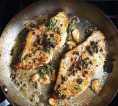 two pieces of fish are cooking in a skillet