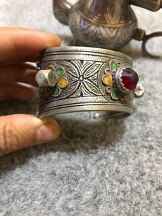 Beautiful antique silver berber bracelet from the Anti Atlas region in Morocco, around 1950. The decoration is very refined, there's some remains of niello deco and enamel in yellow ,blue and green. This Bracelet show an exquisite quality of engraved work with flower motifs. The center stone is an antique glass in red color. High quality of silver, very smooth and nice patina. Min Width : 3,2cm Max Width : 4,7cm Inner diameter : 6cm Weight : 77,3cm Traditional Inlay Cuff Bangle Bracelet, Traditional Inlay Bracelets As Gift, Traditional Inlay Bracelets Perfect For Gifts, Bohemian Silver Bracelets With Meenakari, Traditional Engraved Bracelets, Traditional Engraved Collectible Bracelets, Silver Meenakari Bangle Bracelet, Traditional Engraved Collectible Bangle, Vintage Meenakari Jewelry For Ceremonial Occasions