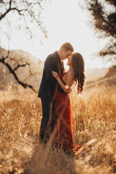 a man and woman standing in tall grass