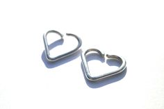 two heart shaped earrings sitting on top of a white surface