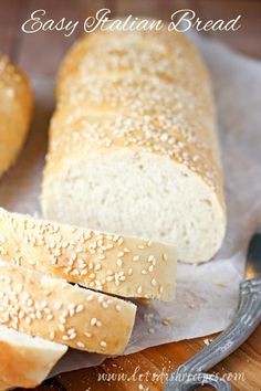 two loaves of bread sitting on top of a cutting board next to a knife