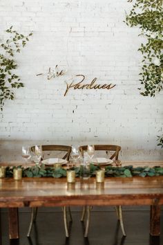 the table is set with place settings and greenery