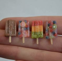 miniature popsicles made with gummy bears and other candies are displayed on a finger